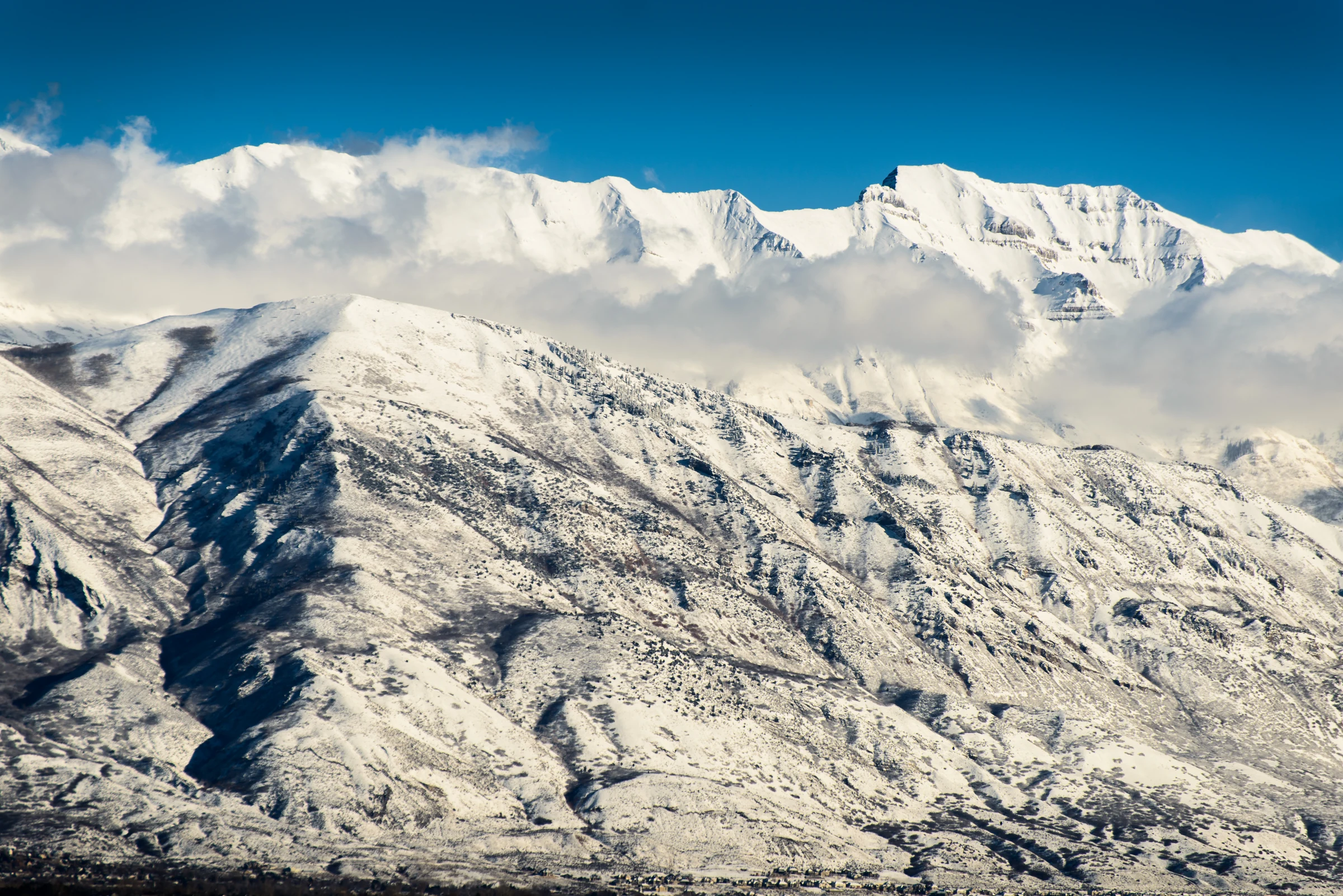 Snow-covered Wasatch mountains rise above Utah County under a clear blue sky